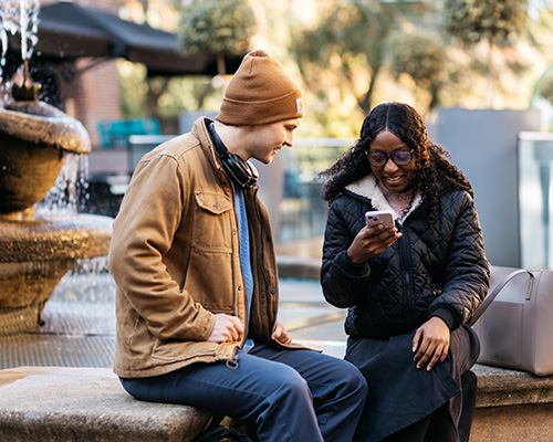 2 students sat having a conversation with one student on their phone