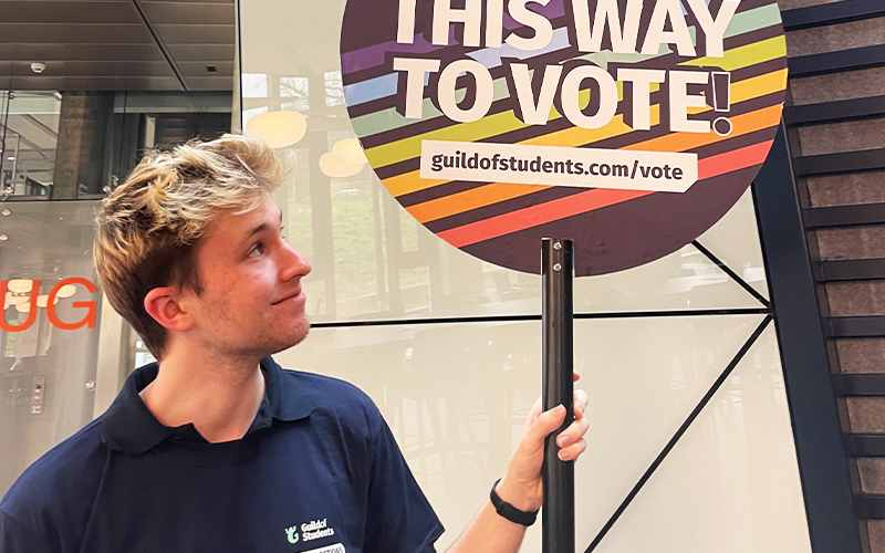 a photo of student staff member with a vote now sign